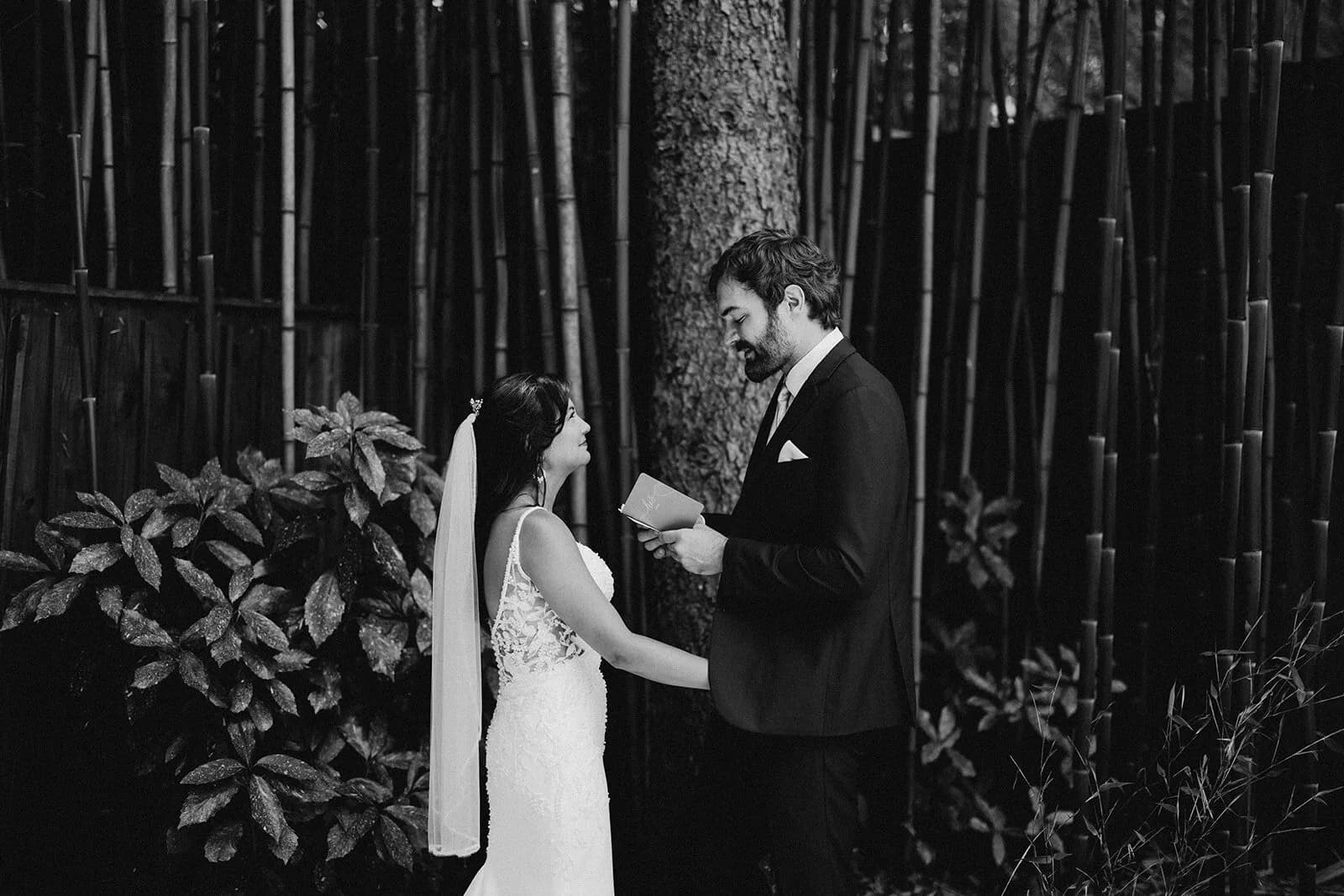 Couple reading vows before bamboo and trees