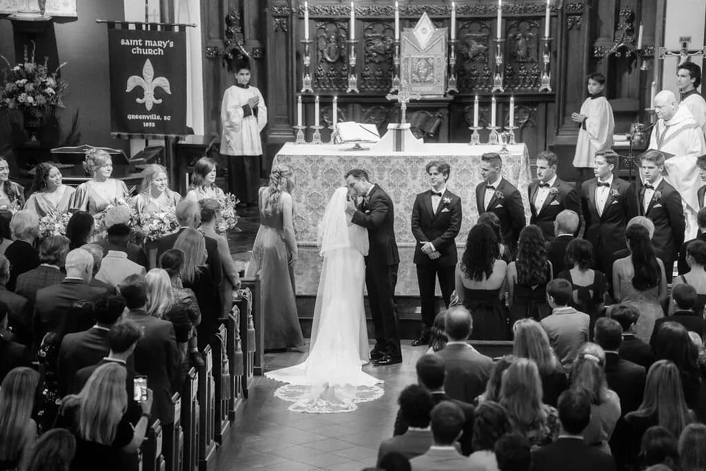 Bride and groom first kiss at the altar in a historic church